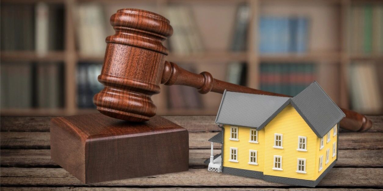A wooden gavel next to a model house.